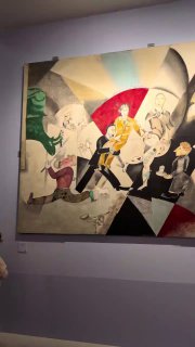 Картина из экспозиции Шагала: сюрреалистическая сцена с фигурами и контрастной палитрой, повешенная на светлой стене зала.