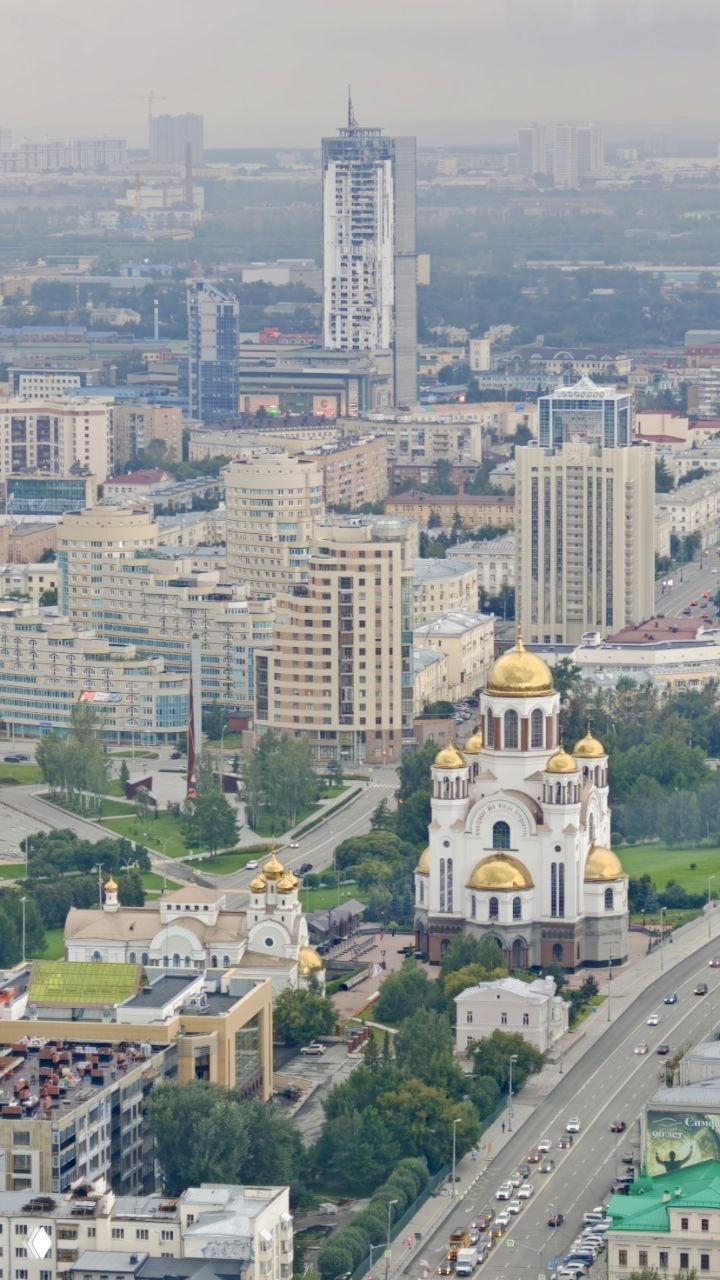 Вид на многоэтажные дома, улицы и золочёные купола Храма на Крови с высоты 186 метров — городской ландшафт и берег Исети.