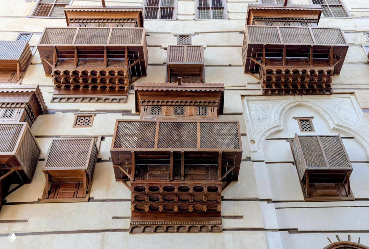 Крупный план ряда пластиково-деревянных балконов с резными подоконниками и орнаментом, вид снизу на архитектурные детали.