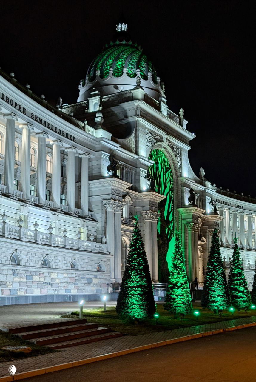 Боковой ракурс здания Дворца земледельцев в Казани с колоннами, декоративной лепниной и зелёной подсветкой на переднем плане.