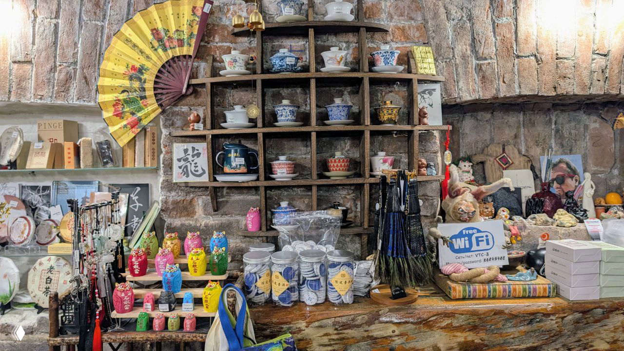 Интерьер сувенирного магазина: полки с чайными сервизами, матрёшками, веером и небольшими сувенирами в стиле Востока, атмосферный вид витрины.