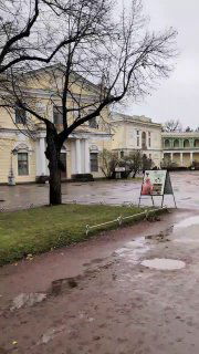 Дворцовый двор и прогулочная зона при пасмурной погоде: дорожки, вывески и архитектура хозяйственных строений рядом с основным корпусом.