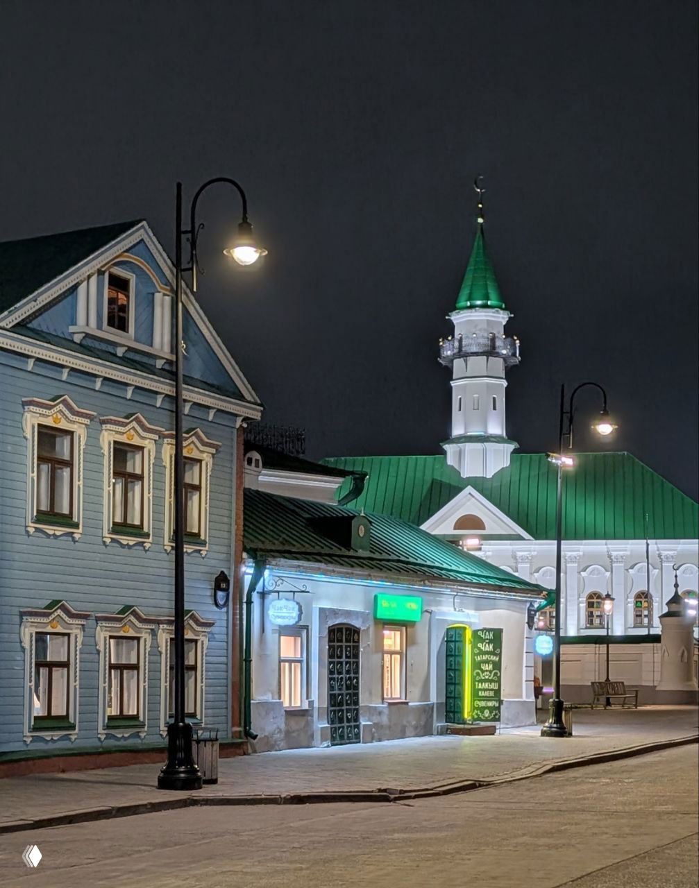 Традиционные деревянные дома и мечеть с зелёной крышей в старом квартале Казани, освещённые уличными фонарями в ночное время.
