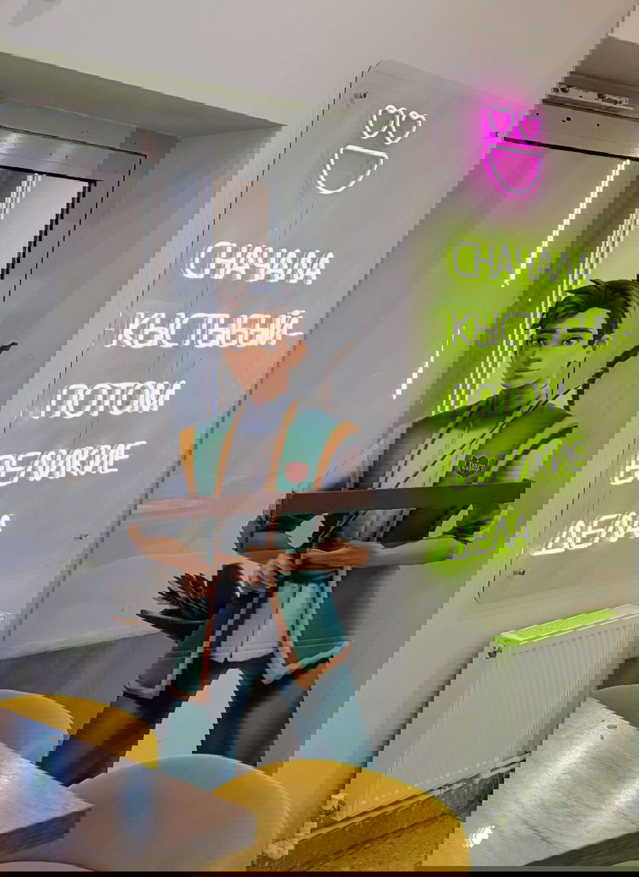 Интерьерное фото с неоновым плакатом и ростовой фигурой персонажа — пример современной городской креативной локации или кафе в Казани.