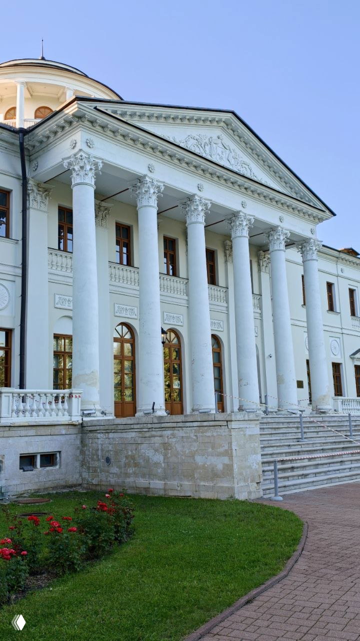 Портик с коринфскими колоннами и подъёмной лестницей у входа в главный дом Остафьево: архитектурные детали, балюстрада и клумба с розами у подножия ступеней.