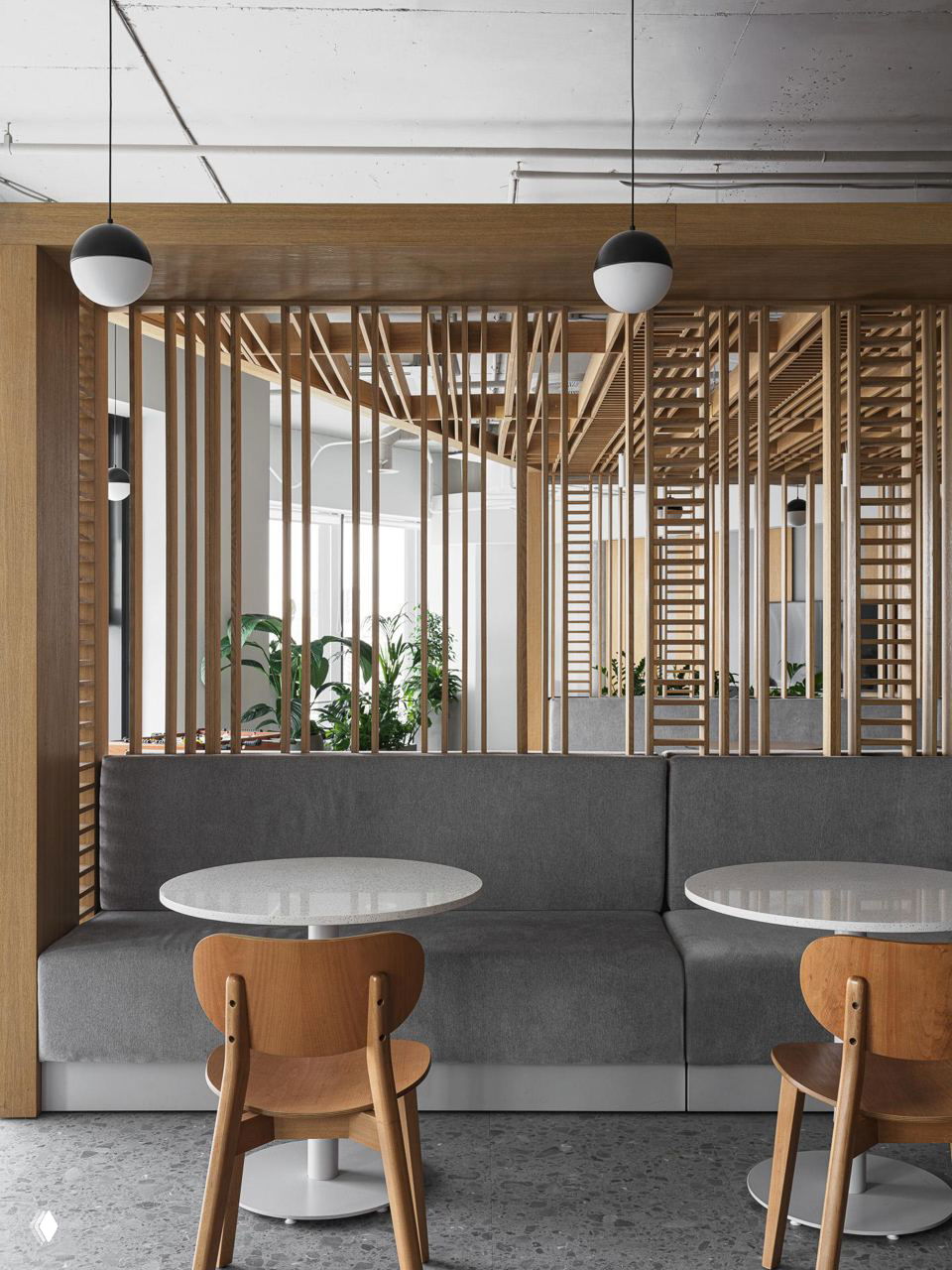 Зона отдыха с диваном, деревянными вертикальными планками-перегородками, столиками и растениями на фоне окон, часть оформления офиса 2ГИС в Москве.