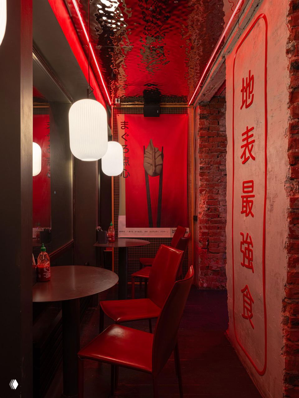 Узкий коридор заведения с подвесными фонарями, плакатами и большим тканевым баннером с иероглифами на фоне кирпичной стены и красных акцентов.