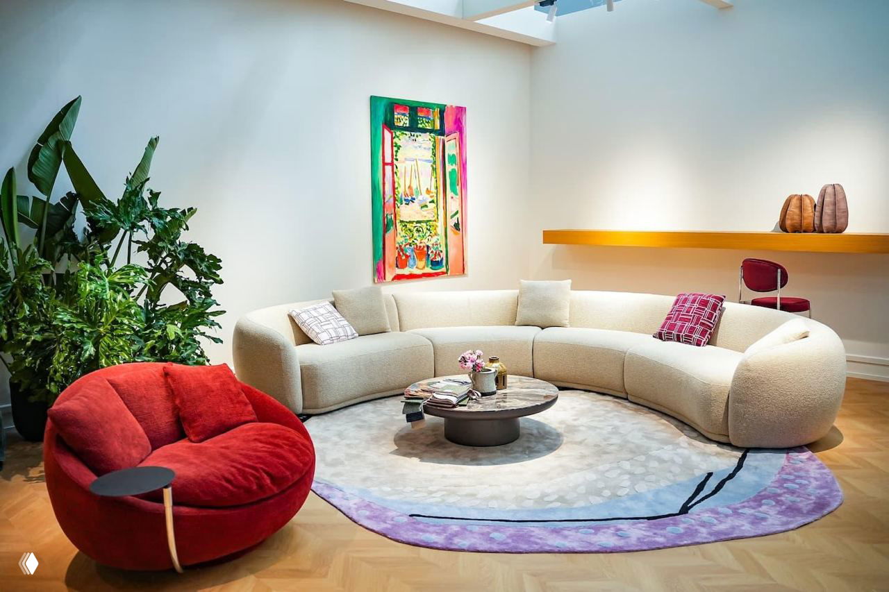 Интерьерная зона с модульным диваном, круглым журнальным столиком и цветной картиной на стене в стиле выставочной инсталляции.