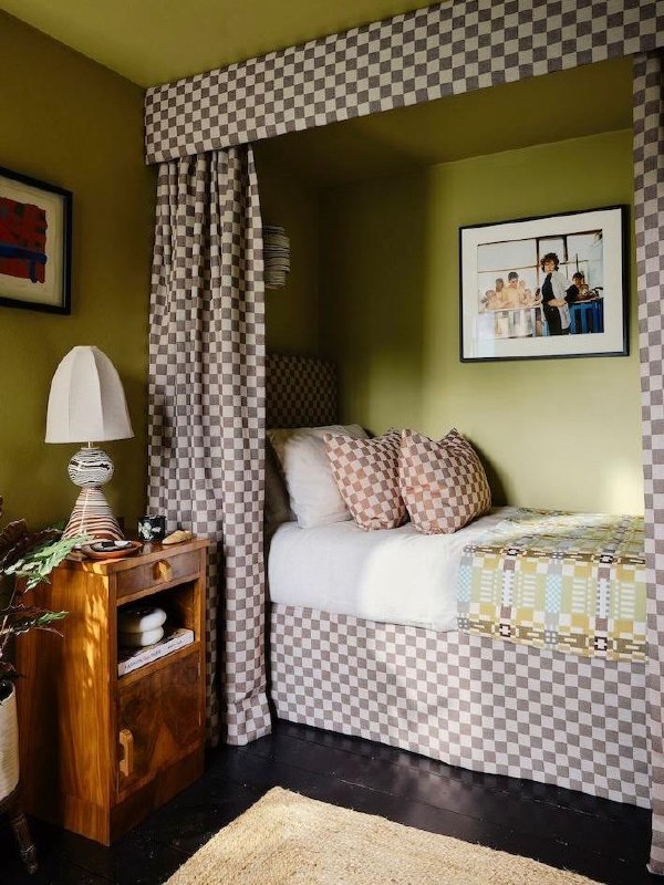 Уютная ниша для гостевой с зелёной окантовкой, клетчатым текстилем, декоративными подушками и тумбочкой — компактный и продуманный интерьерный приём.