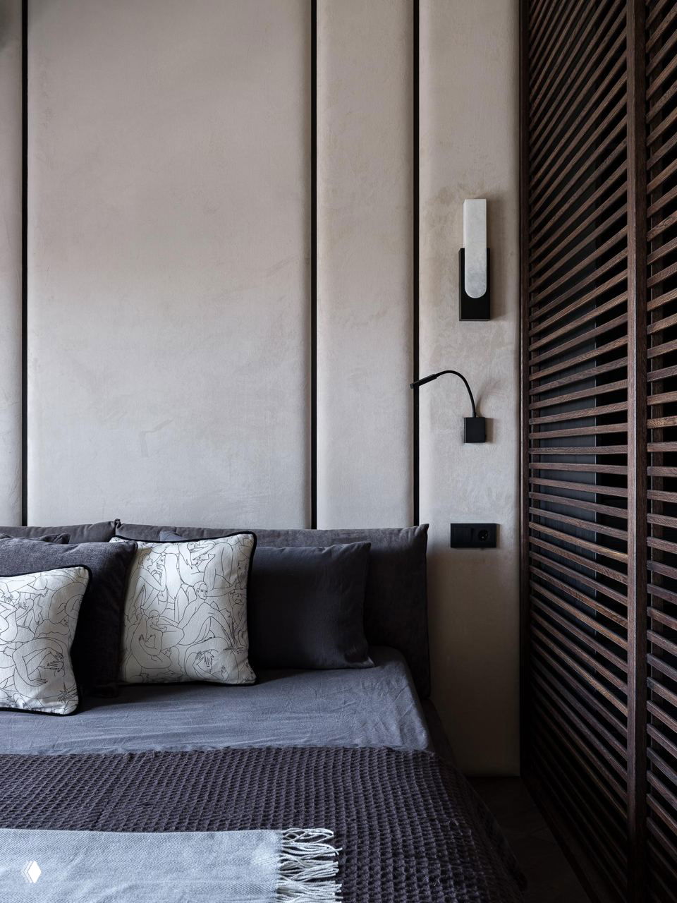 Спальня с мягкой придающей уют обивкой, панельной отделкой стены и декоративными подушками в контрастных оттенках — акцент на текстурах.