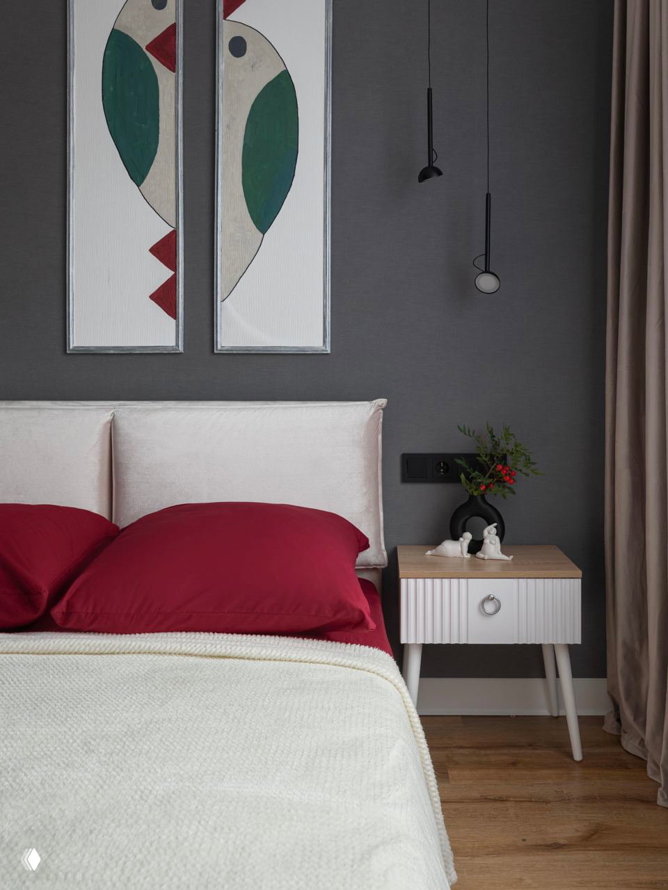 Крупный план изголовья кровати с бордовыми наволочками на светлом покрывале, настенные декоративные панели и тёмный фон стены.