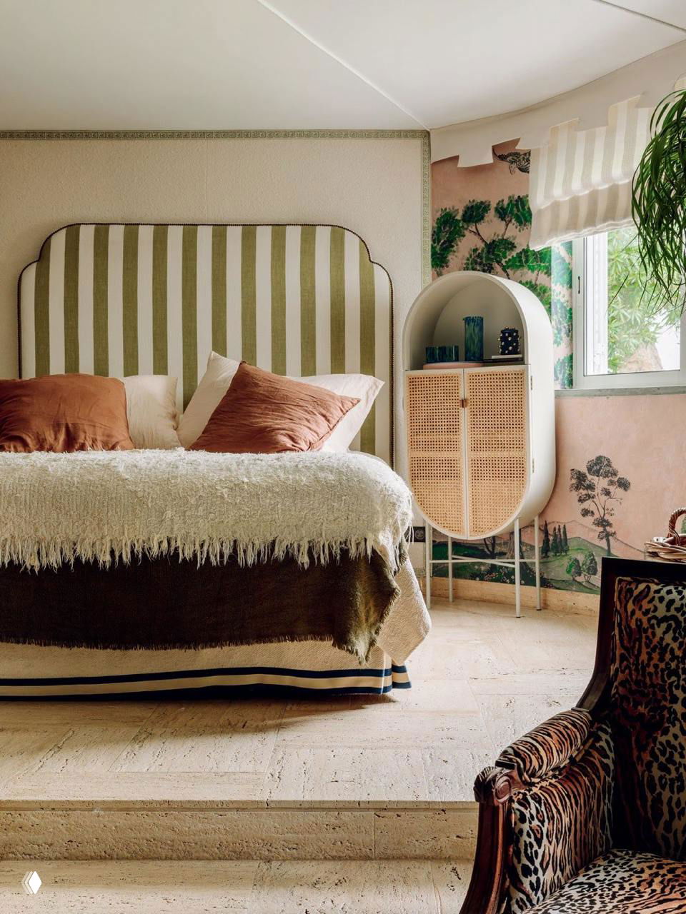 Спальня с полосатым изголовьем, фактурным текстилем и овальным плетёным шкафом; мягкая палитра в сочетании с растительными мотивами.