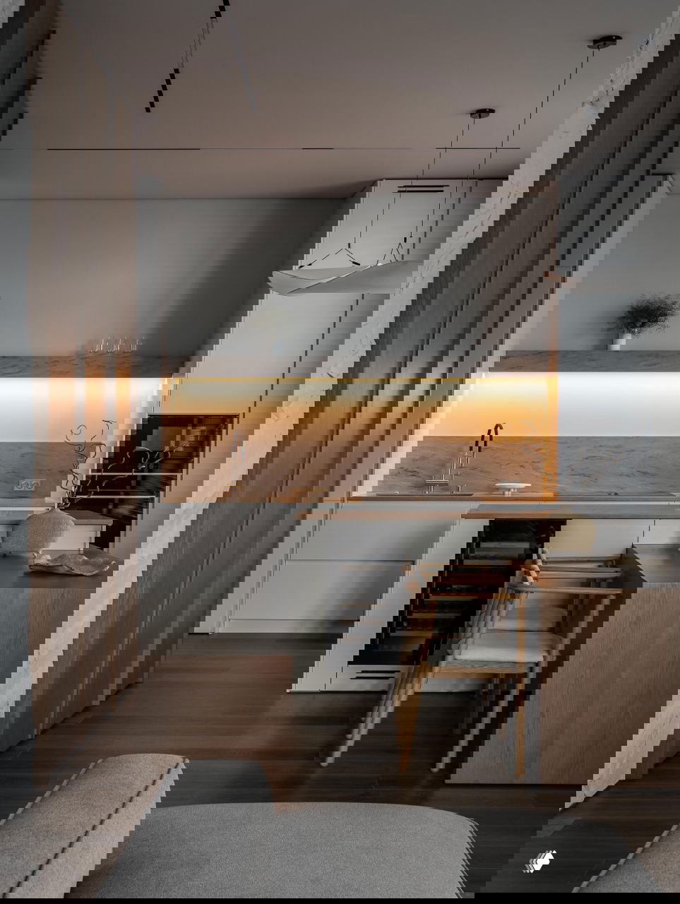 Кухня-гостиная: сдержанная кухня с подсветкой рабочей зоны, барная стойка из дерева и светлые фасады в минималистичном стиле джапанди.