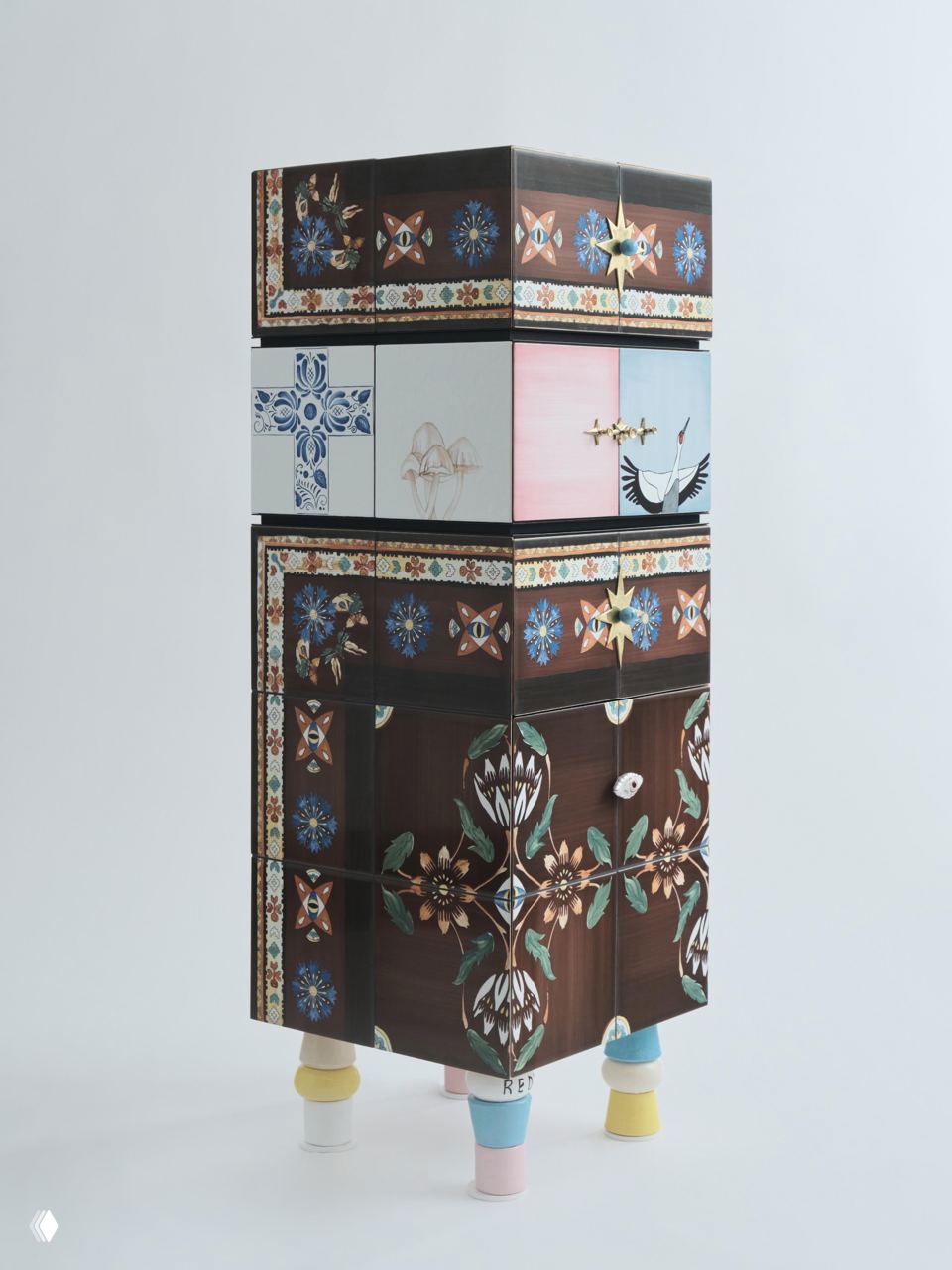 Стеклянные и керамические элементы, составленные в многоярусный шкаф с разными декоративными панелями и разноцветными ножками, демонстрирующие междисциплинарный подход коллекции.