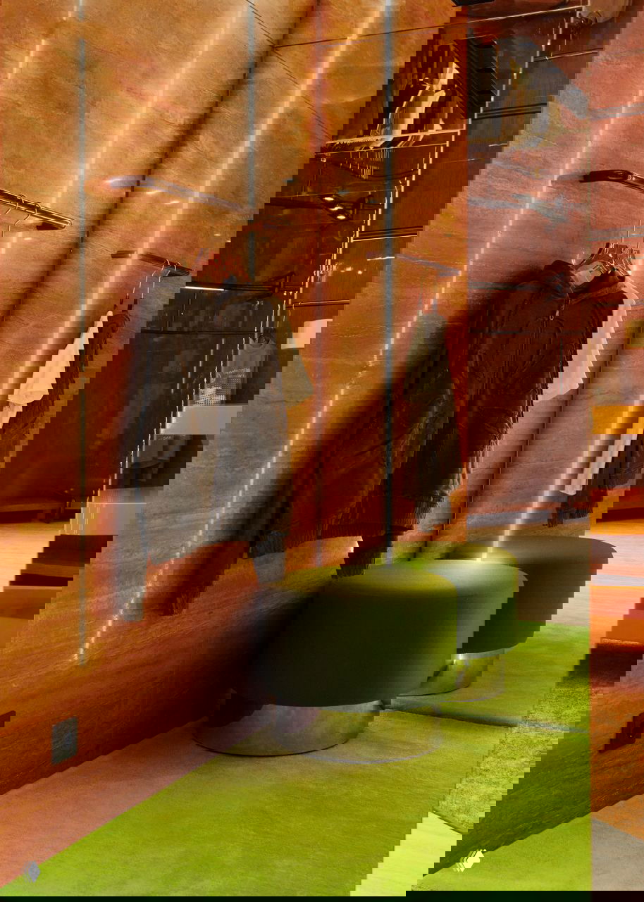 Угловой фрагмент интерьера: зеркальная стена, подсветка вдоль вертикальных панелей и ярко‑зелёные пуфы на фоне розово‑оранжевого пола.