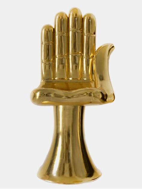 Крупный план золотого кресла в форме раскрытой руки с глянцевой полированной поверхностью и чёткими объёмными линиями, нейтральный фон.