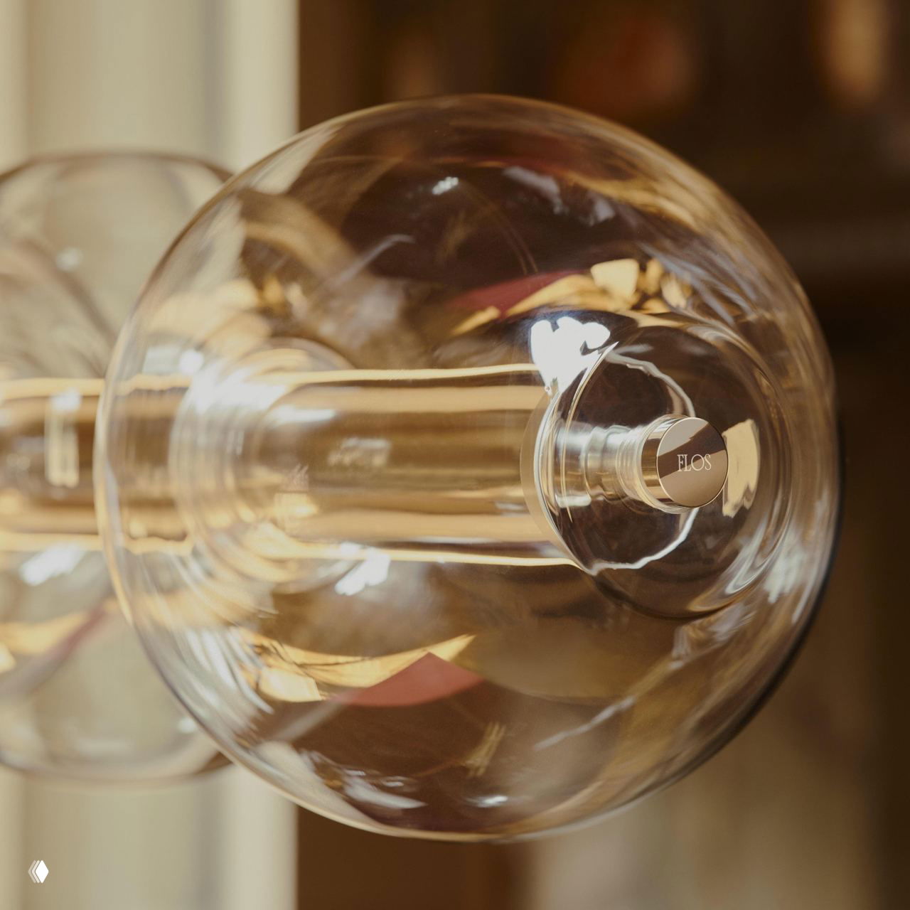 Макрофото шарового модуля со металлической заглушкой с логотипом Flos, подчёркивается тонкая обработка и прозрачность стекла.