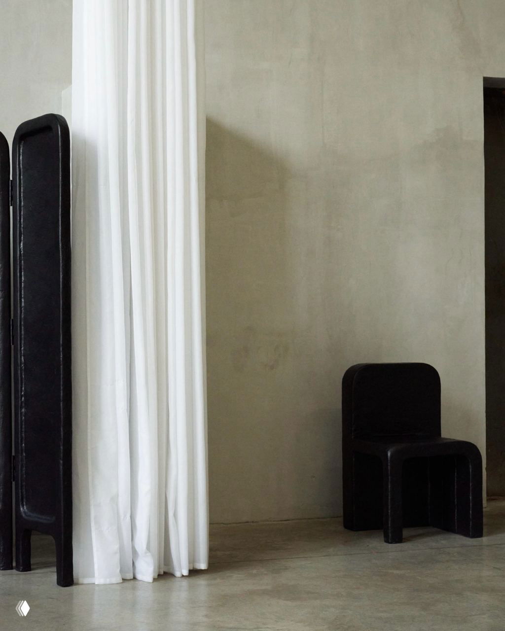 Чёрный стул и трёхпанельная ширма коллекции Echo у длинной белой занавеси на фоне светло-серой стены; акцент на текстуру материала.