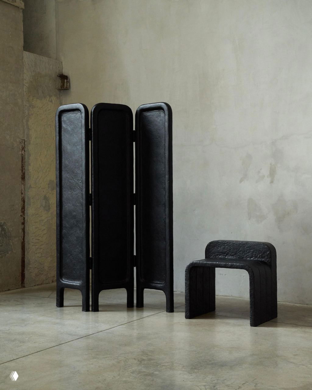 Трёхсекционная чёрная ширма и низкий табурет Echo в минималистичном помещении; видна фактура фанеры и переработанной бумаги на поверхности.