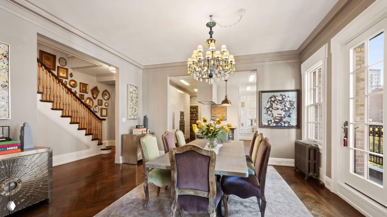 Столовая зона и лестничный холл в дуплексе: большое обеденное место, люстра и вид на деревянную лестницу с декоративными элементами в историческом доме 1910 года.