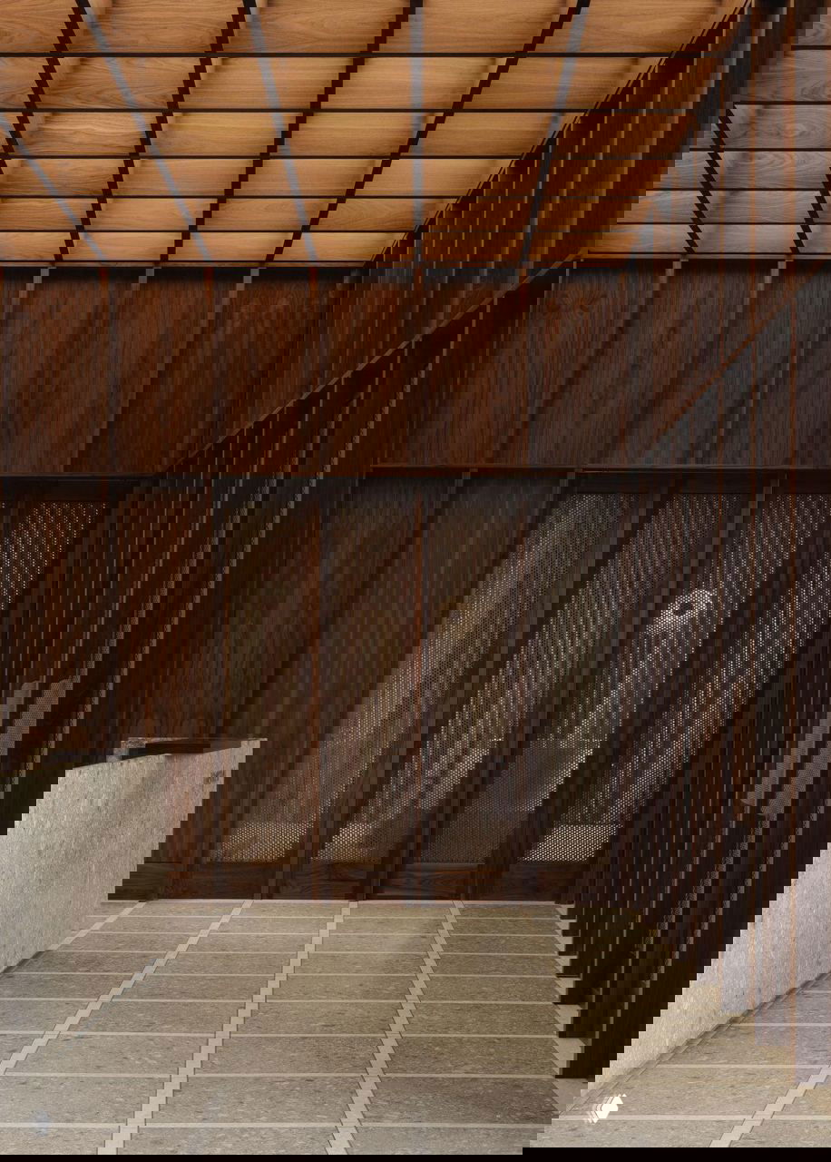 Широкий интерьер с высокими деревянными панелями, ритмом колонн и решётчатым потолком — тёплая палитра и крупные текстуры в коридоре клиники.