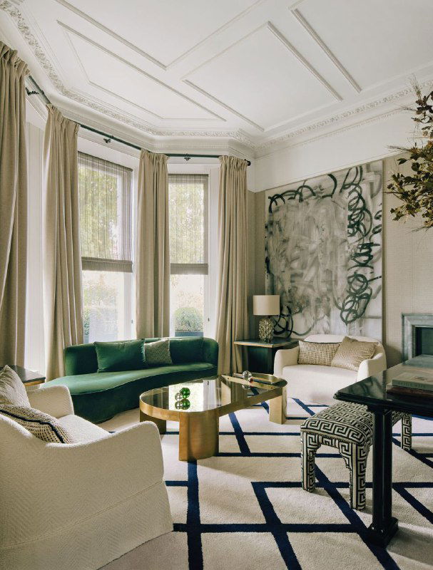 Светлая гостиная с зелёным диваном, высокими шторами и большой абстрактной живописью у окна: сочетание классической лепнины и современных тканей.