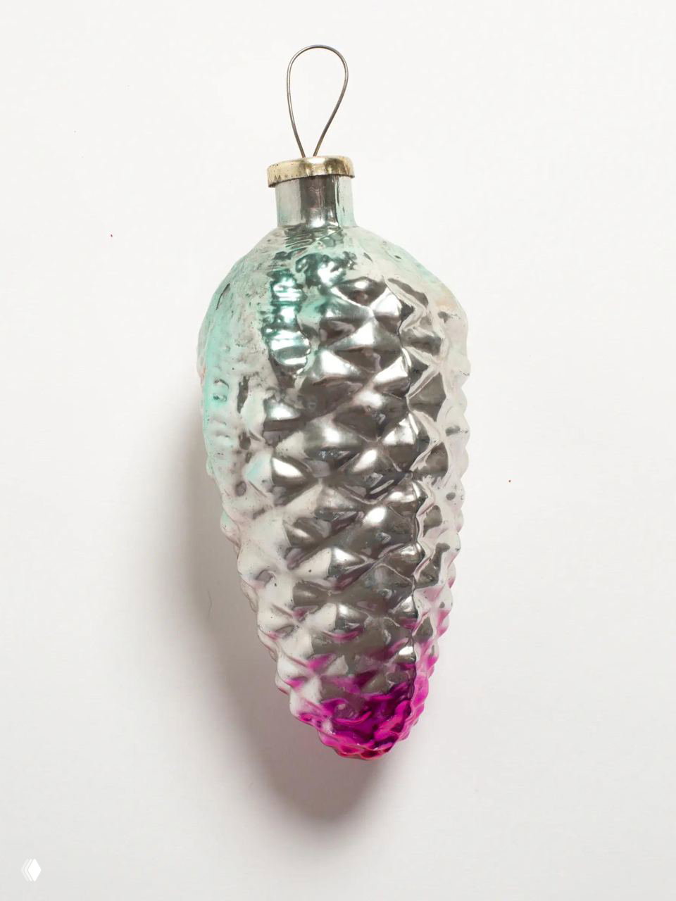 Крупный план стеклянной шишки‑игрушки с серебристым покрытием и розовым градиентом; видна оригинальная старинная патина и потертости.