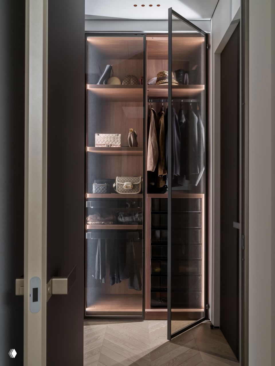 Гардеробная с тонированными стеклянными дверцами, внутренней подсветкой и аккуратно организованными полками для сумок и одежды; элегантная функциональность.
