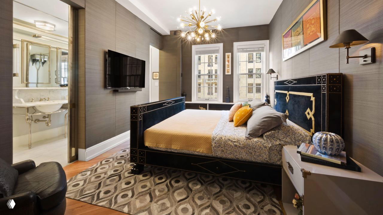 Спальня в дуплексе с большой кроватью, декоративным изголовьем, ковром и окнами в историческом здании Манхэттена, интерьер выполнен в спокойной цветовой гамме.