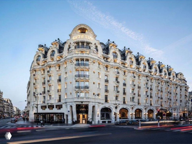Внешний фасад Mandarin Oriental Lutetia в Париже с белым каменным корпусом и богатыми ар-нуво и ар-деко декоративными деталями на перекрёстке.
