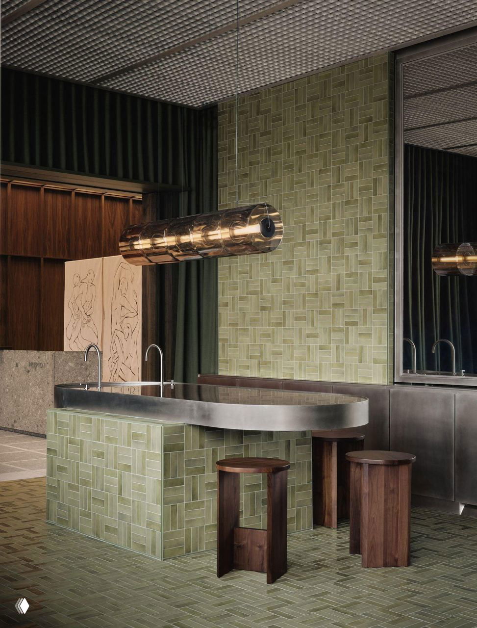 Зона с зелёной плиткой и изогнутой металлической столешницей, сочетание керамики и матового металла в утилитарной части интерьера медцентра.