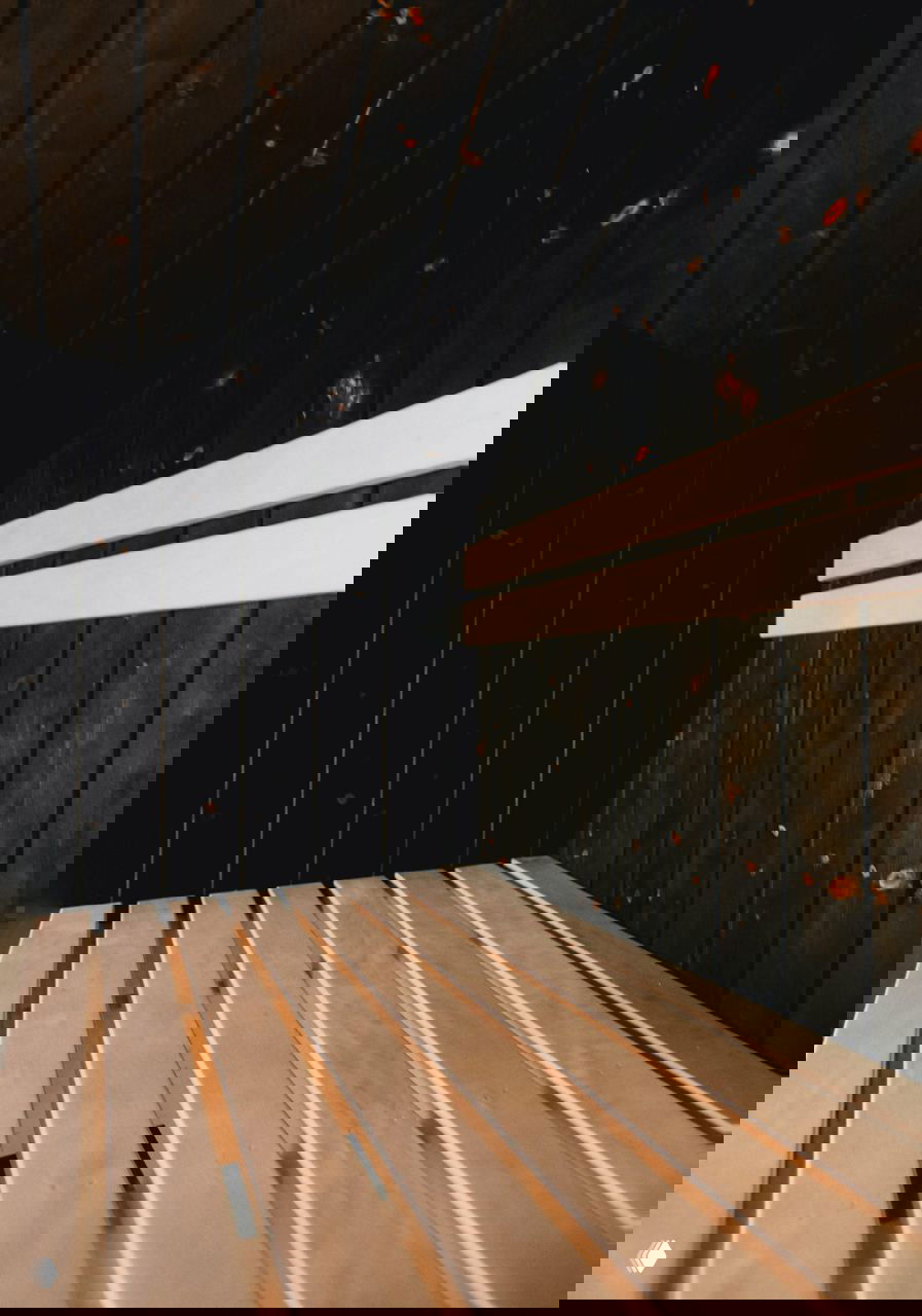 Интерьер парилки с обожжённой внутренней обшивкой в технике Shou Sugi Ban: тёмные стеновые панели и светлые деревянные лавки создают контраст и уют.