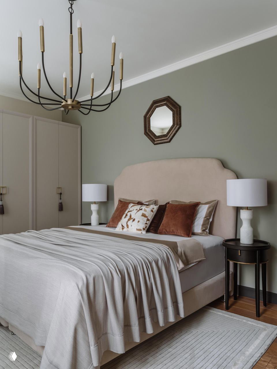 Спальня в современной классике: мягкое изголовье бежевого тона, приглушённые зелёные стены, подвесная люстра и спокойная текстильная гамма.
