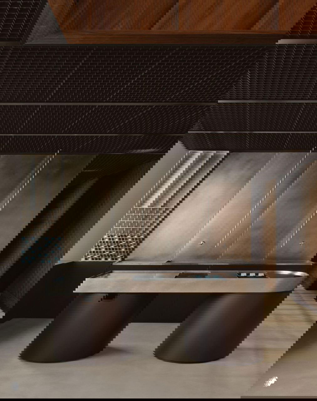 Металлическая рабочая поверхность и встроенные модули на фоне тёмных стен — холодные матовые металлы смягчаются тёплыми деревянными элементами интерьера.