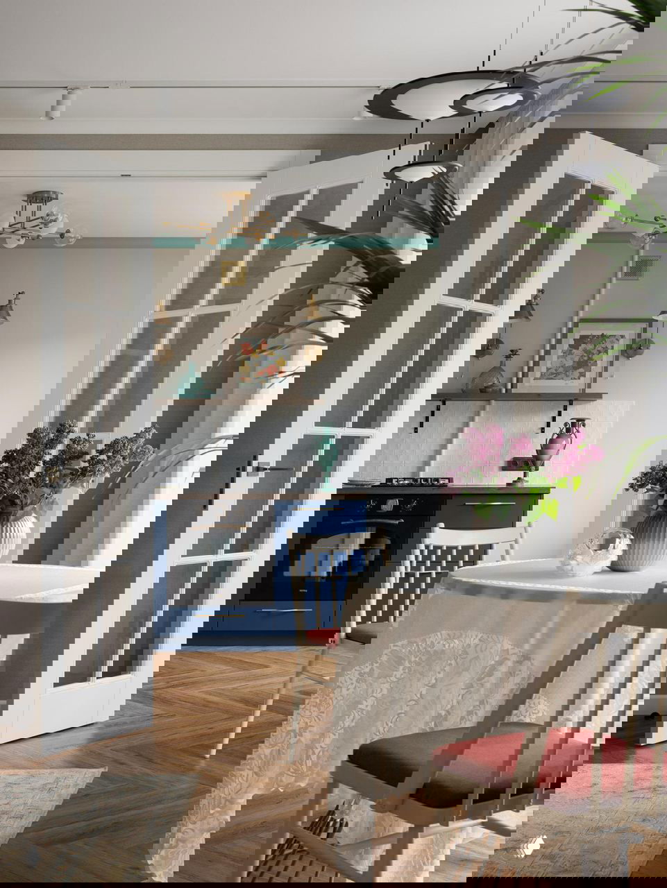 Вид через французские двери на обеденную зону и кухню с синими фасадами, текстиль и вазоны создают домашнюю атмосферу в квартире 49 м².