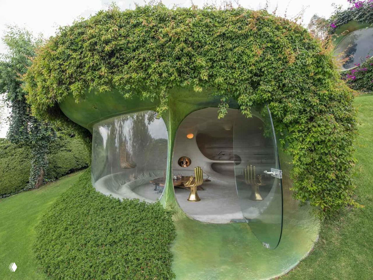 Входная ниша с двумя круглыми проемами и прозрачной дверью: интерьер просматривается через гладкие органические формы.