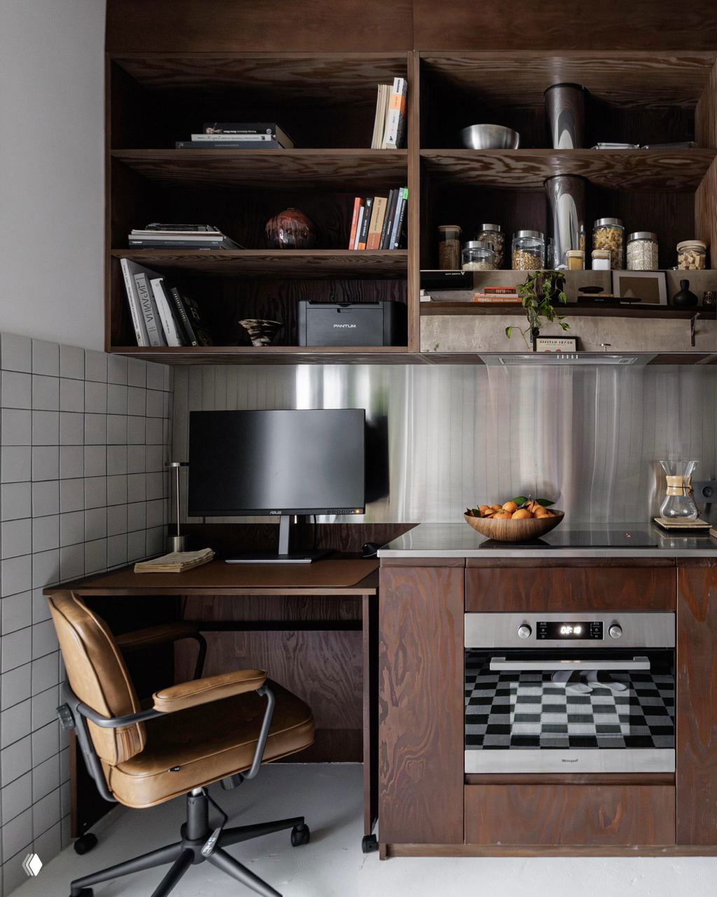 Кухонный уголок с деревянными шкафами, открытыми полками и рабочим местом: монитор, металлическая фартук-панель и аккуратные баночки на полках