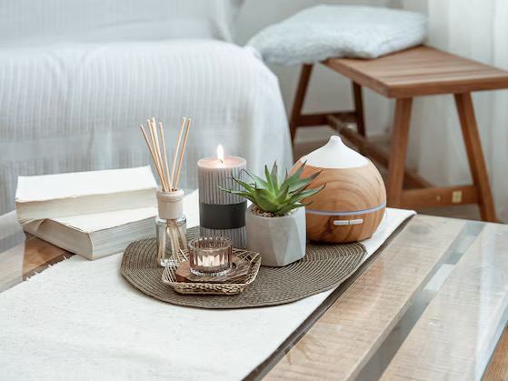 Светлый интерьерный натюрморт с аромадиффузором, ароматической свечей и аромадиффузором‑увлажнителем на столе в скандинавском стиле с мягкими текстурами, студийная съемка.