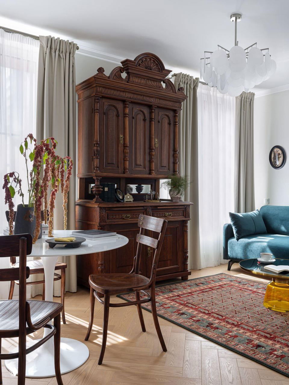 Классический деревянный буфет в сочетании с современной мягкой мебелью и ковром — смешение стилей и использование винтажных предметов в гостиной.