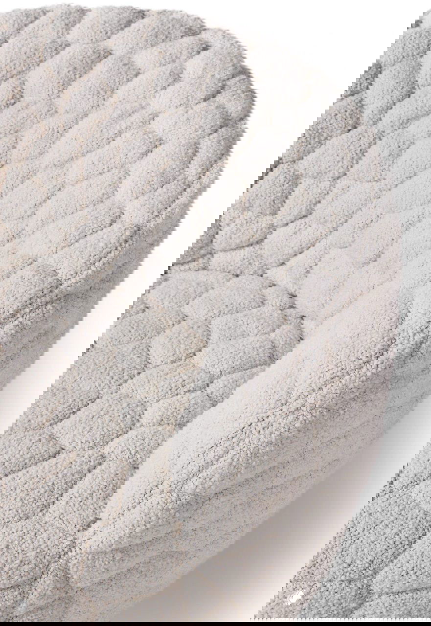 Крупный план текстурной обивки кресла Introvert: стежки и ворсистая поверхность, напоминающая мозаичную «каменную» фактуру.