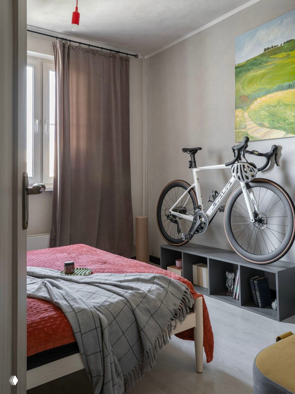 Небольшая спальня с белой кроватью, велосипедом, подвешенным к стене, и тёмными шторами — рациональное использование пространства и цветовые акценты