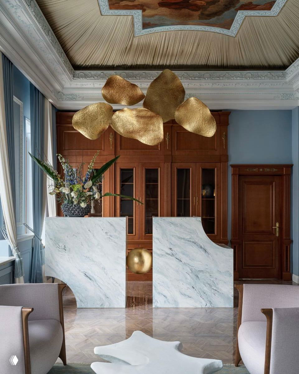Интерьер с лепными потолочными фризами, мраморными стойками и золотистыми элементами освещения в неоклассическом ключе. Представлен в подборке ADDAWARDS 2025.