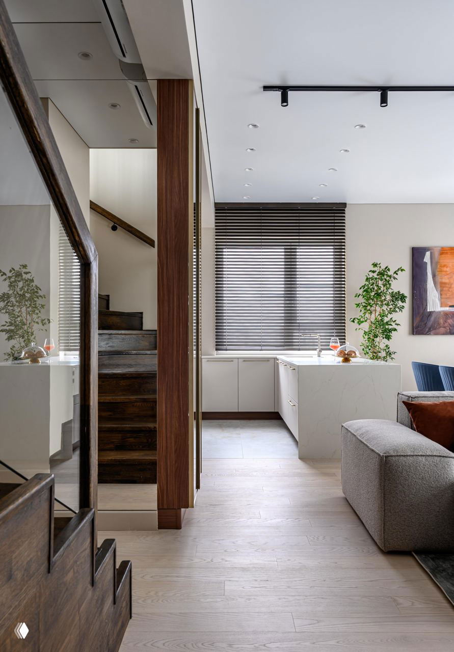 Общий вид гостиной и кухни-нее; светлые стены, тёплый пол и жалюзи на окне создают спокойную, функциональную зону открытой планировки.