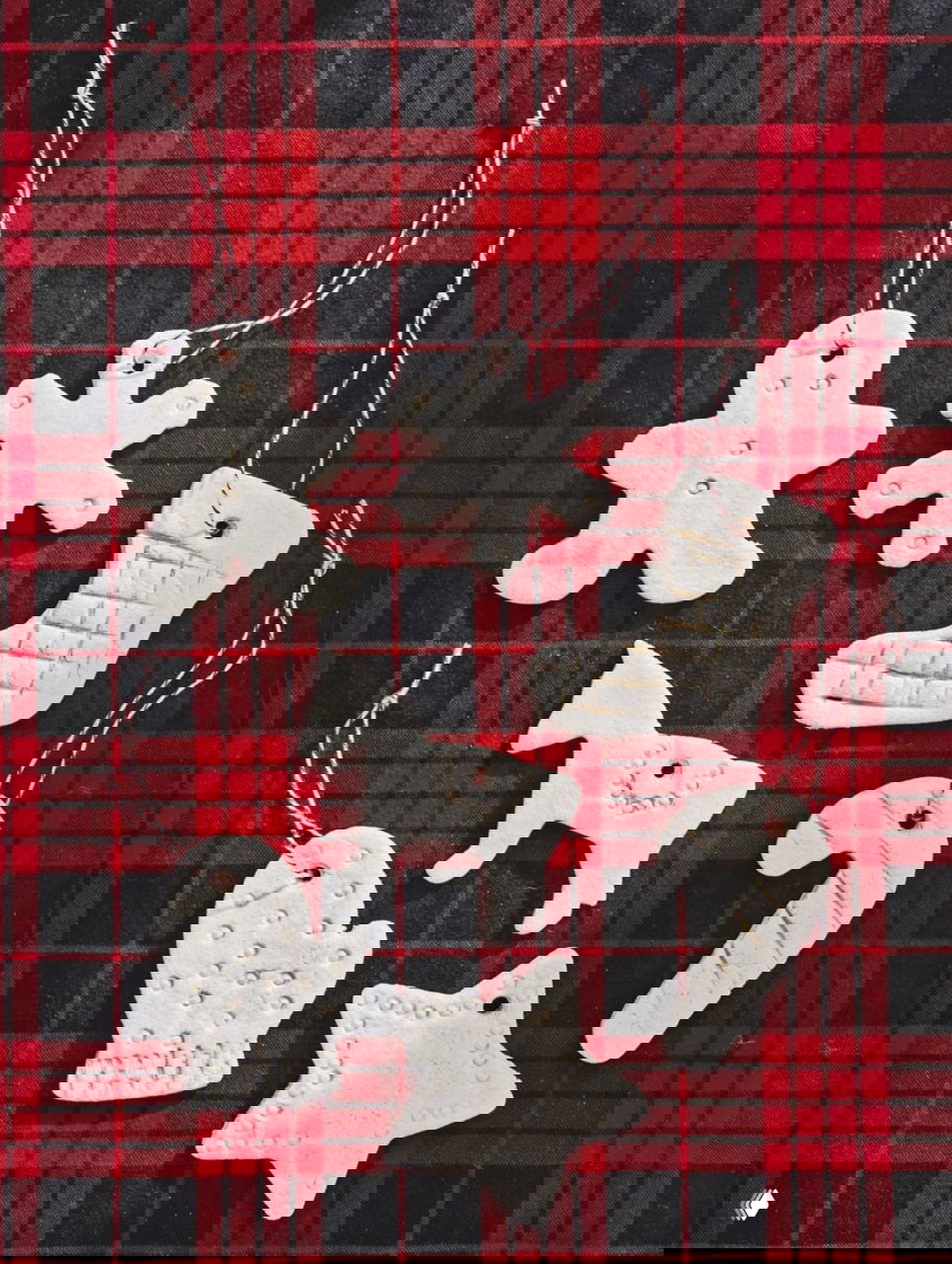 Белые фигурки из солёного теста — человечек, снежинка, носок и лошадка — развёрнуты на красной клетчатой ткани как простые ностальгические игрушки.