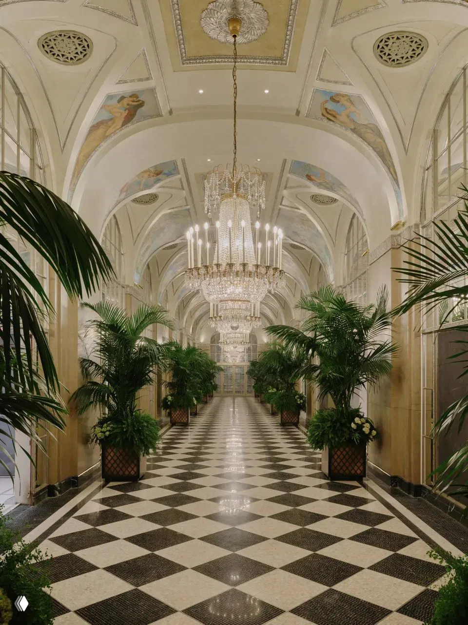 Длинный Серебряный коридор отеля с мраморным шахматным полом, пальмами в кадках и крупными хрустальными люстрами под сводчатым потолком.