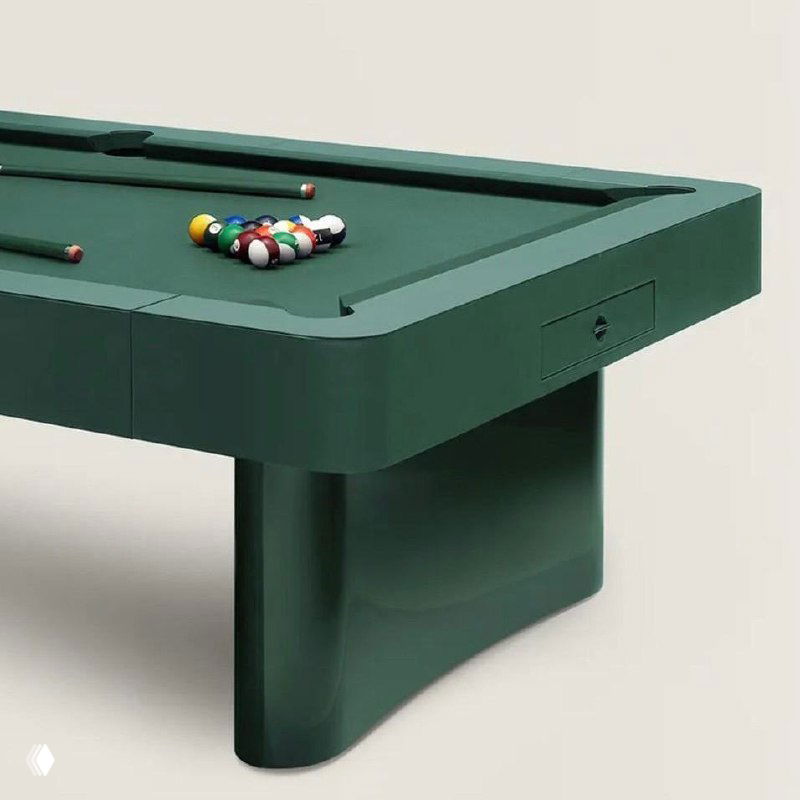 Крупный план угла и опоры стола Hermès: лакированные изогнутые ножки, борта, обитые матовой кожей Vert Anglais, виден аккуратный скрытый ящичек.