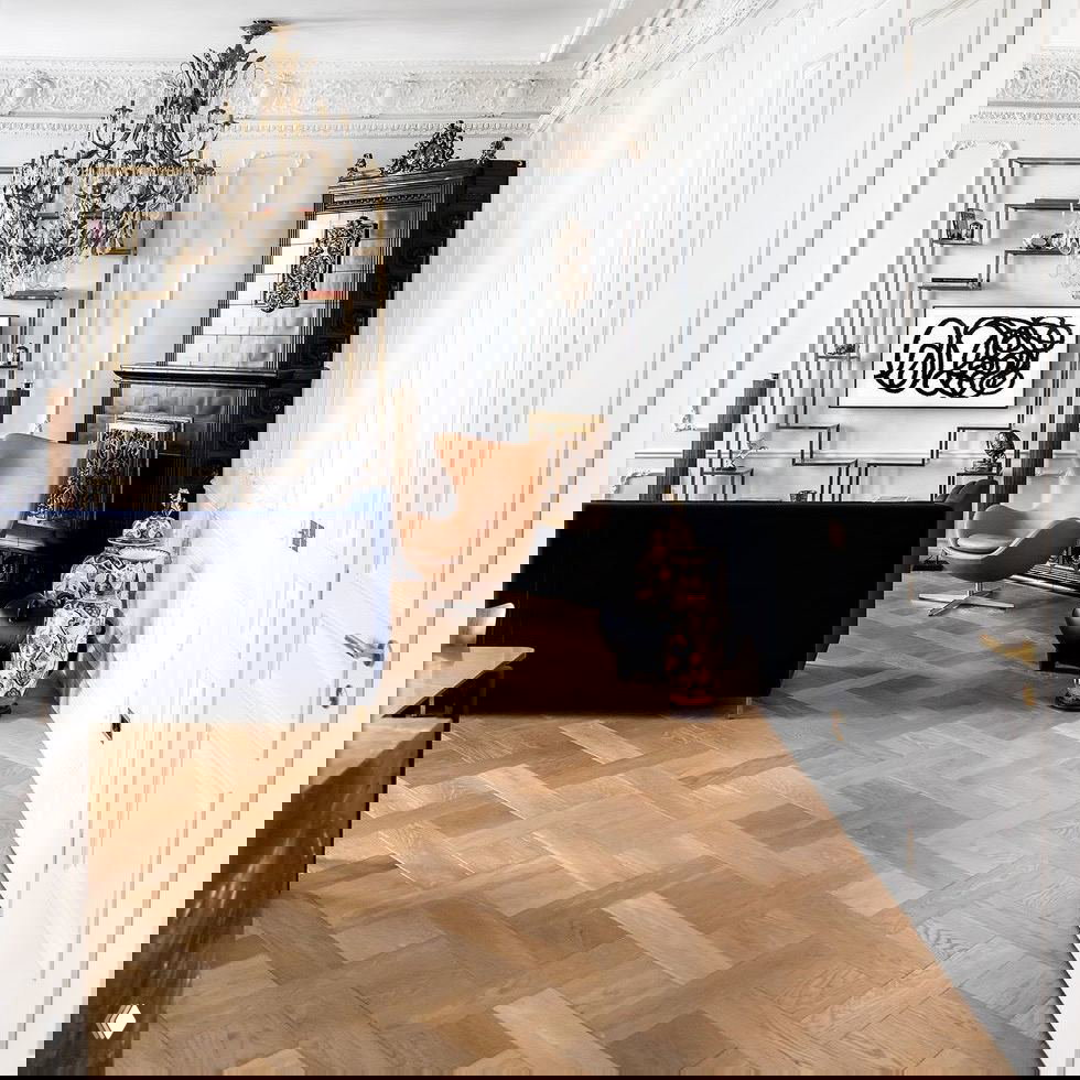 Белая гостиная с лепниной, бронзовой классической люстрой и современными предметами мебели — баланс классики и современного арсенала декора.