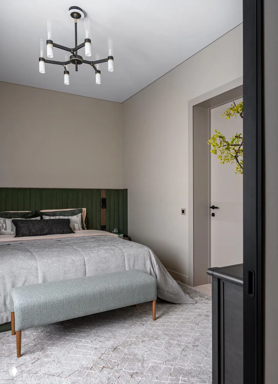 Спальня с приглушёнными тонами, зелёное изголовье и мягкая серая постель; пример использования контрастного текстиля в персональной зоне.