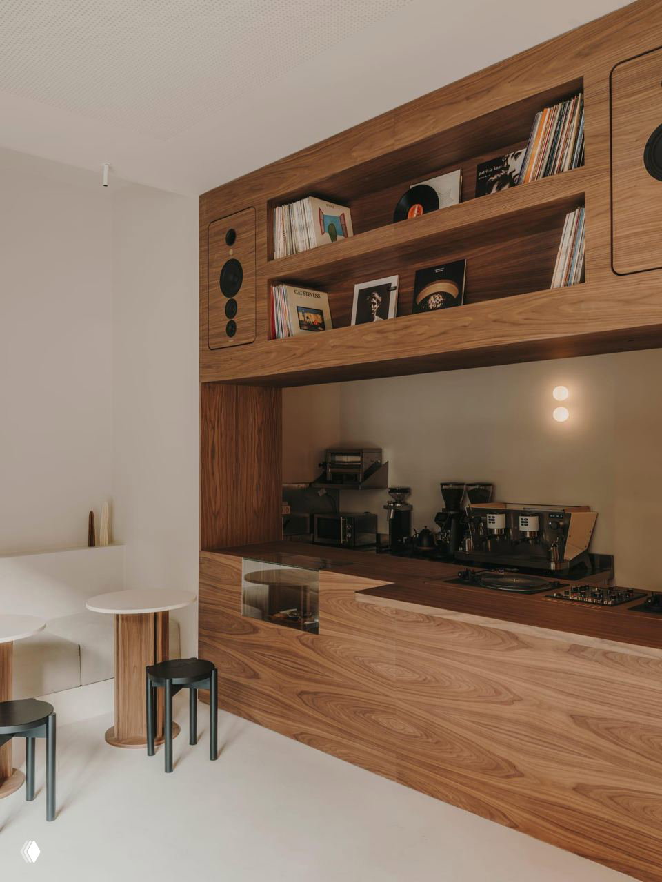 Барная стойка и кофеоборудование в деревянной отделке: полки с виниловыми пластинками над стойкой, кофемашина и аккуратная рабочая зона дизайна студии.