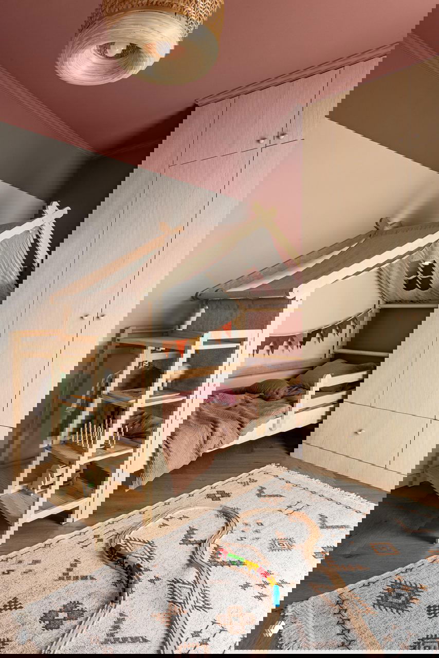 Детская кроватка‑домик из светлого дерева на фоне спокойных стен, игровой коврик и деревянные игрушки; натуральные материалы и уютная атмосфера.